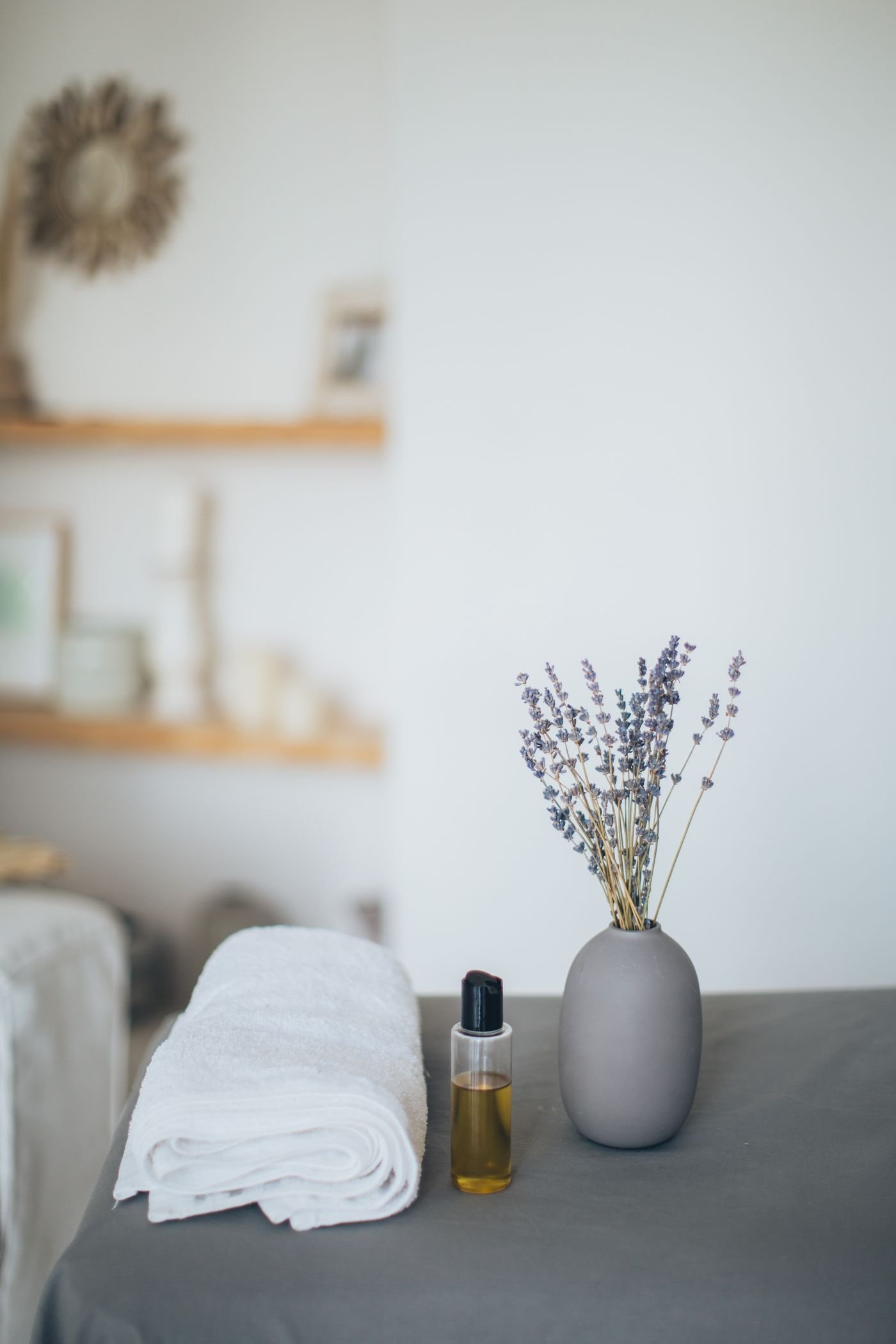 Détail d’une table de massage avec serviette blanche, huile et bouquet de lavande dans le salon Namaste by Emi à Bourg-Saint-Andéol